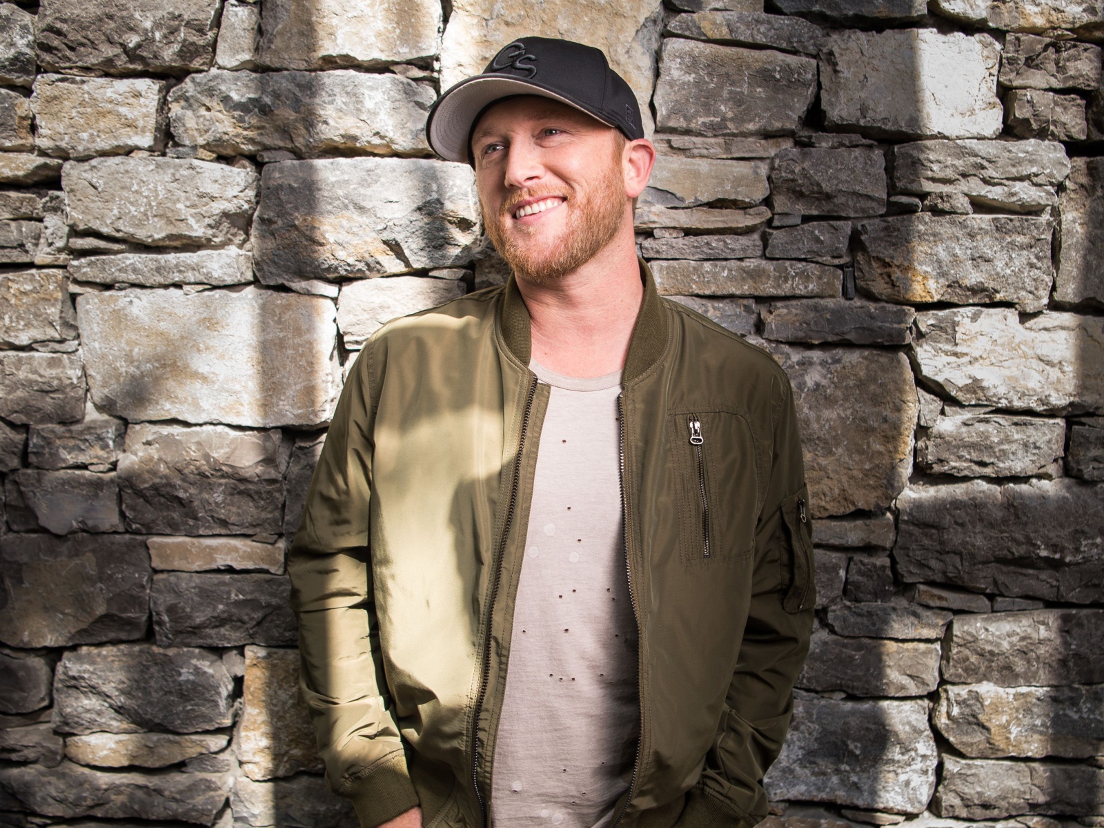 Музыкант Коул Суинделл в бейсболке у стены