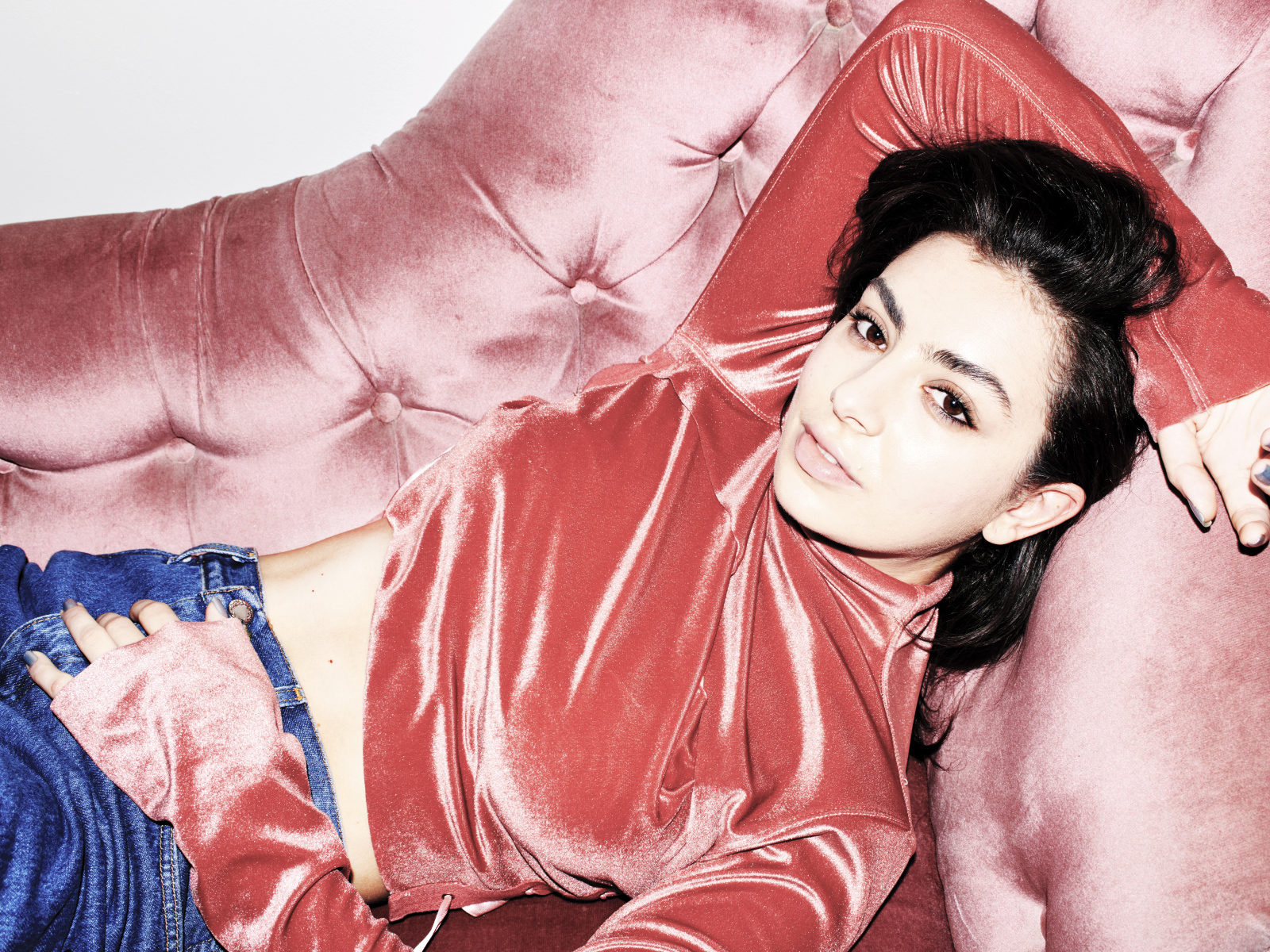 Молодая девушка Charli XCX лежит на диване