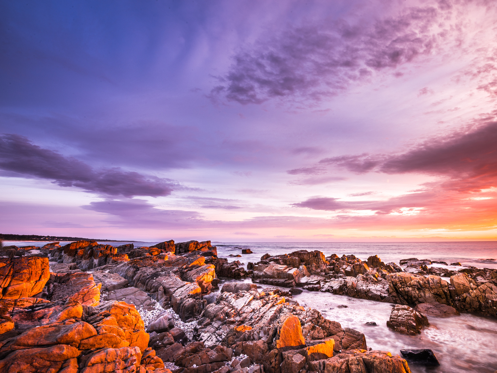 Каменный берег в море на закате солнца