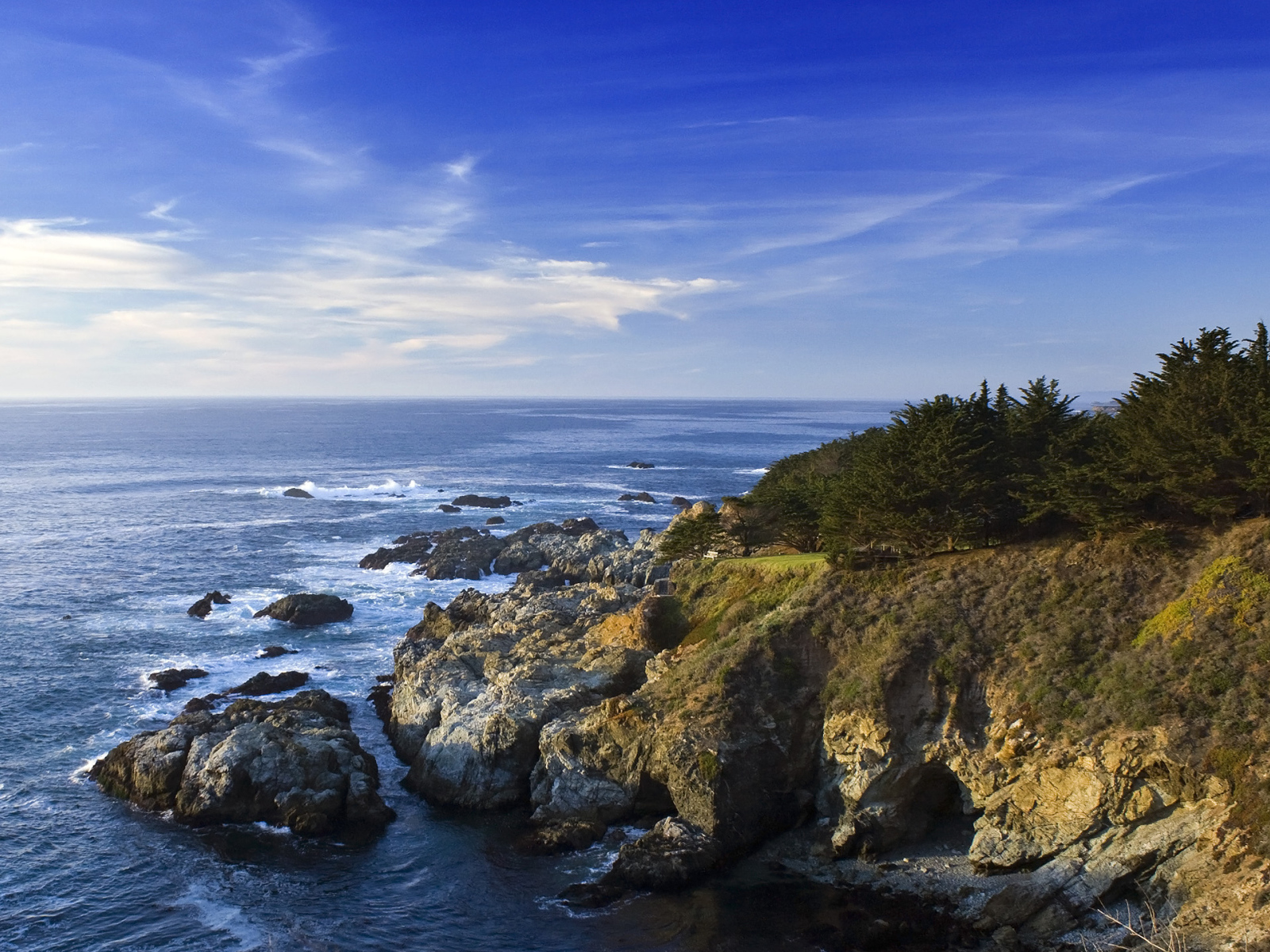 Каменные скалы береговой линии в океане под голубым небом