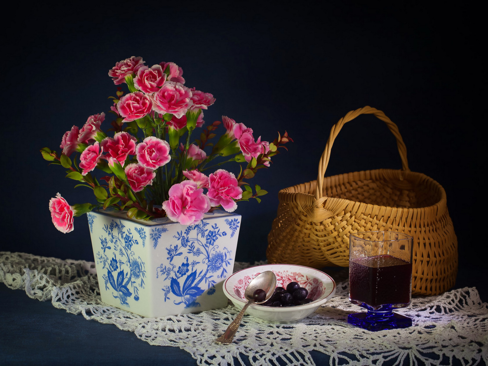 Букет гвоздик в красивой вазе на столе с корзиной и соком