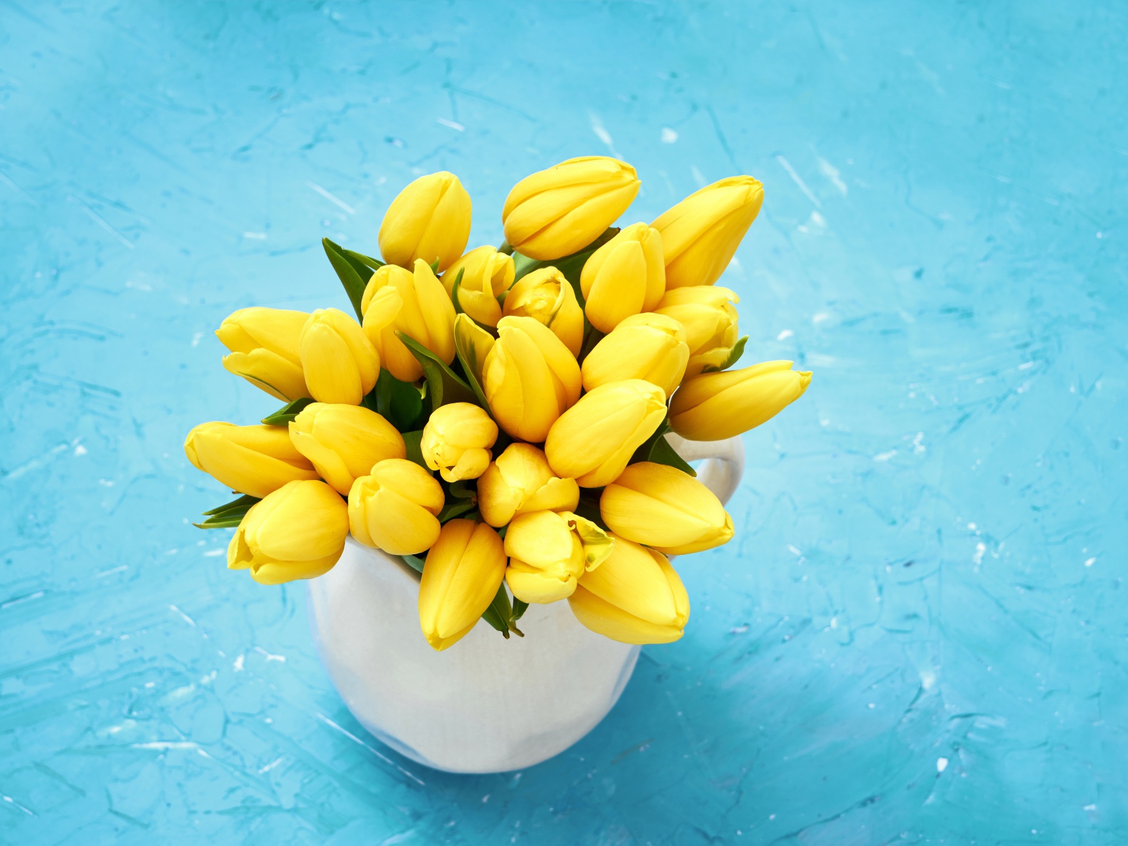 Букет оранжевых тюльпанов в белой вазе на голубом фоне