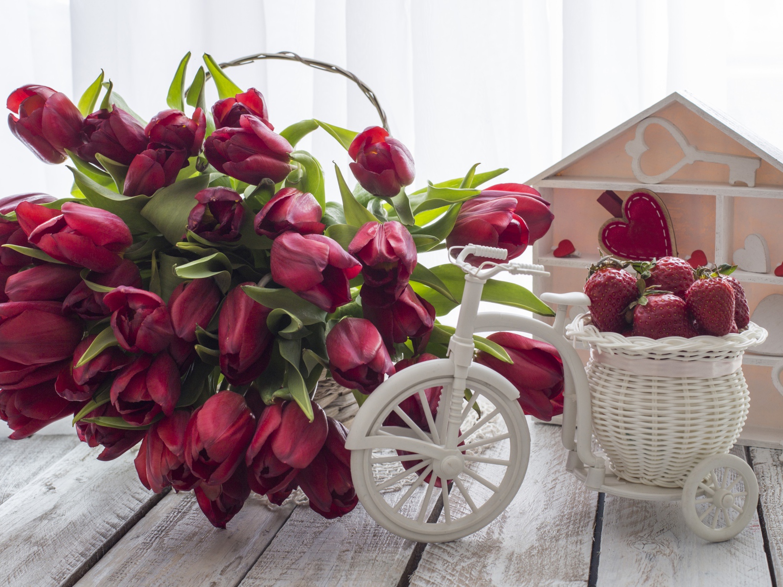 Красивый букет красных тюльпанов на столе с клубникой 