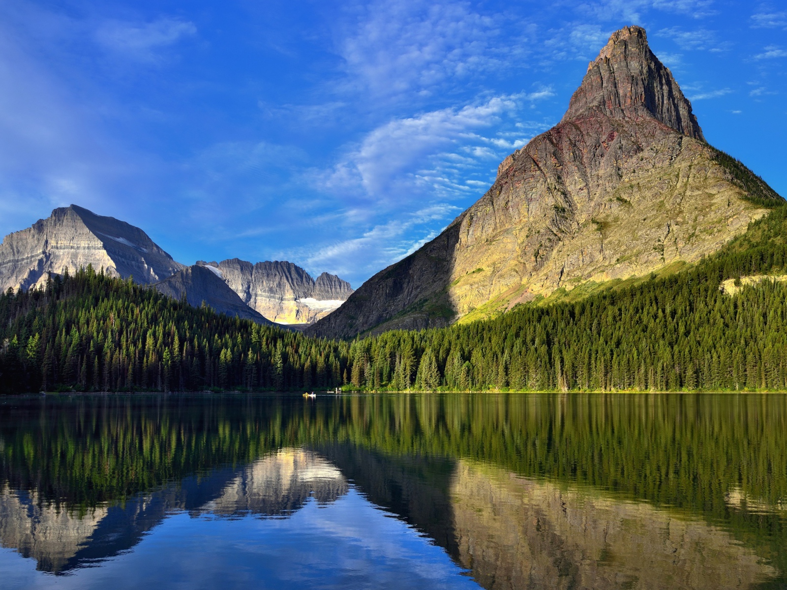 Каменные горы под голубым небом отражаются в воде