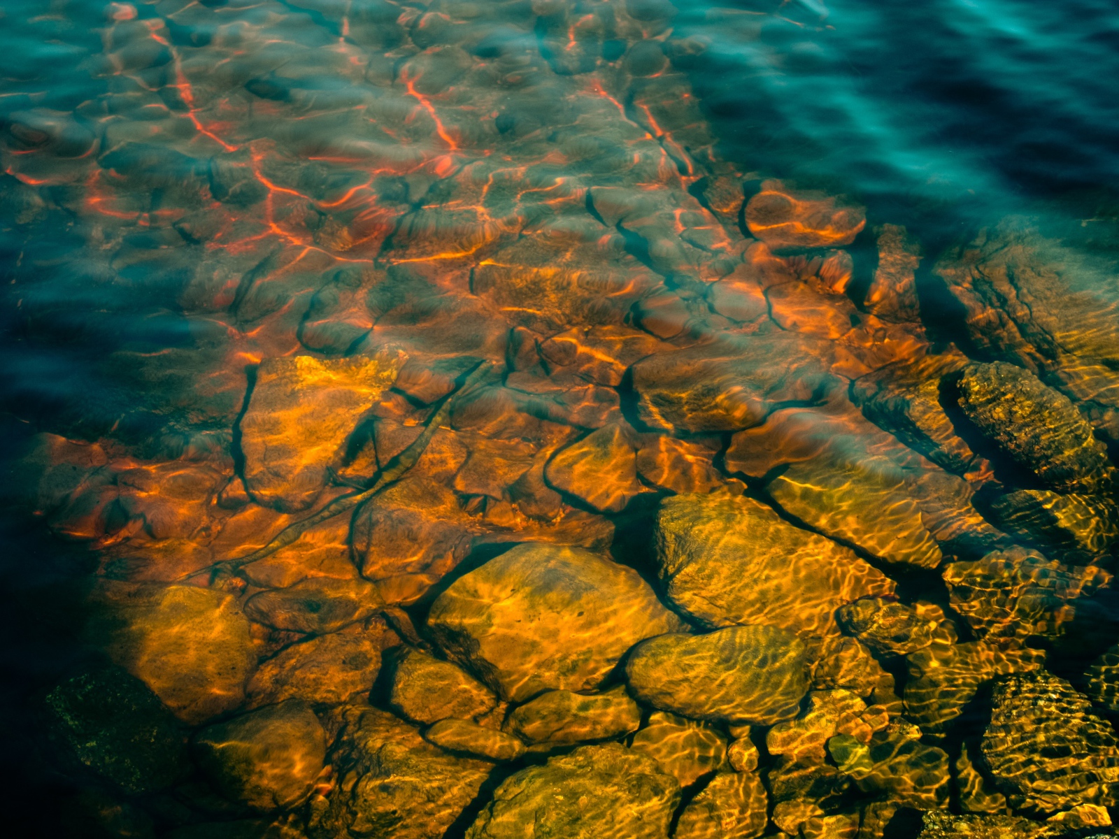Камни на дне озера с чистой водой в лучах солнца