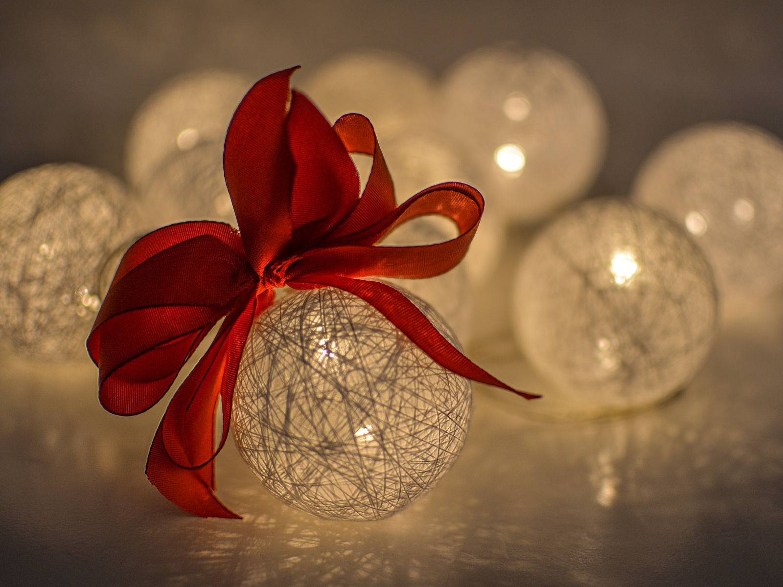 Красивый елочный шар с белых нитей с красным бантом