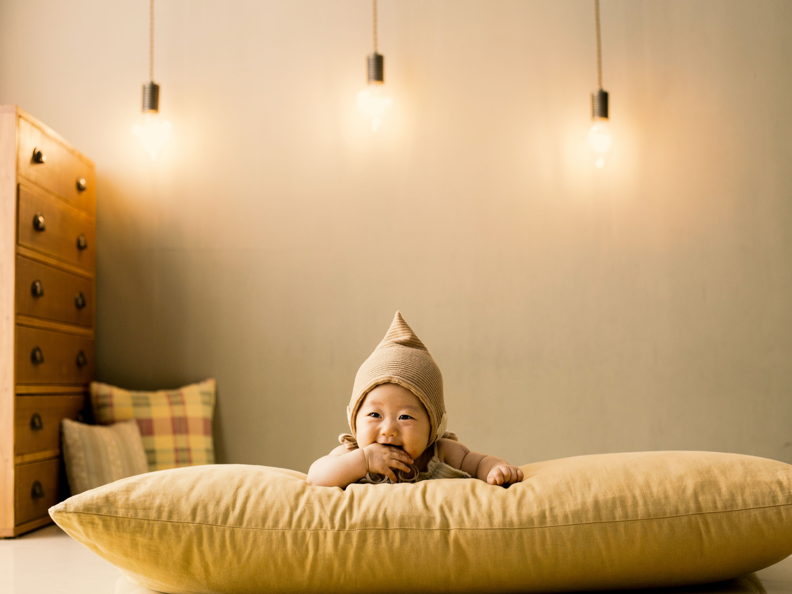 Маленький ребенок лежит на подушке под лампами