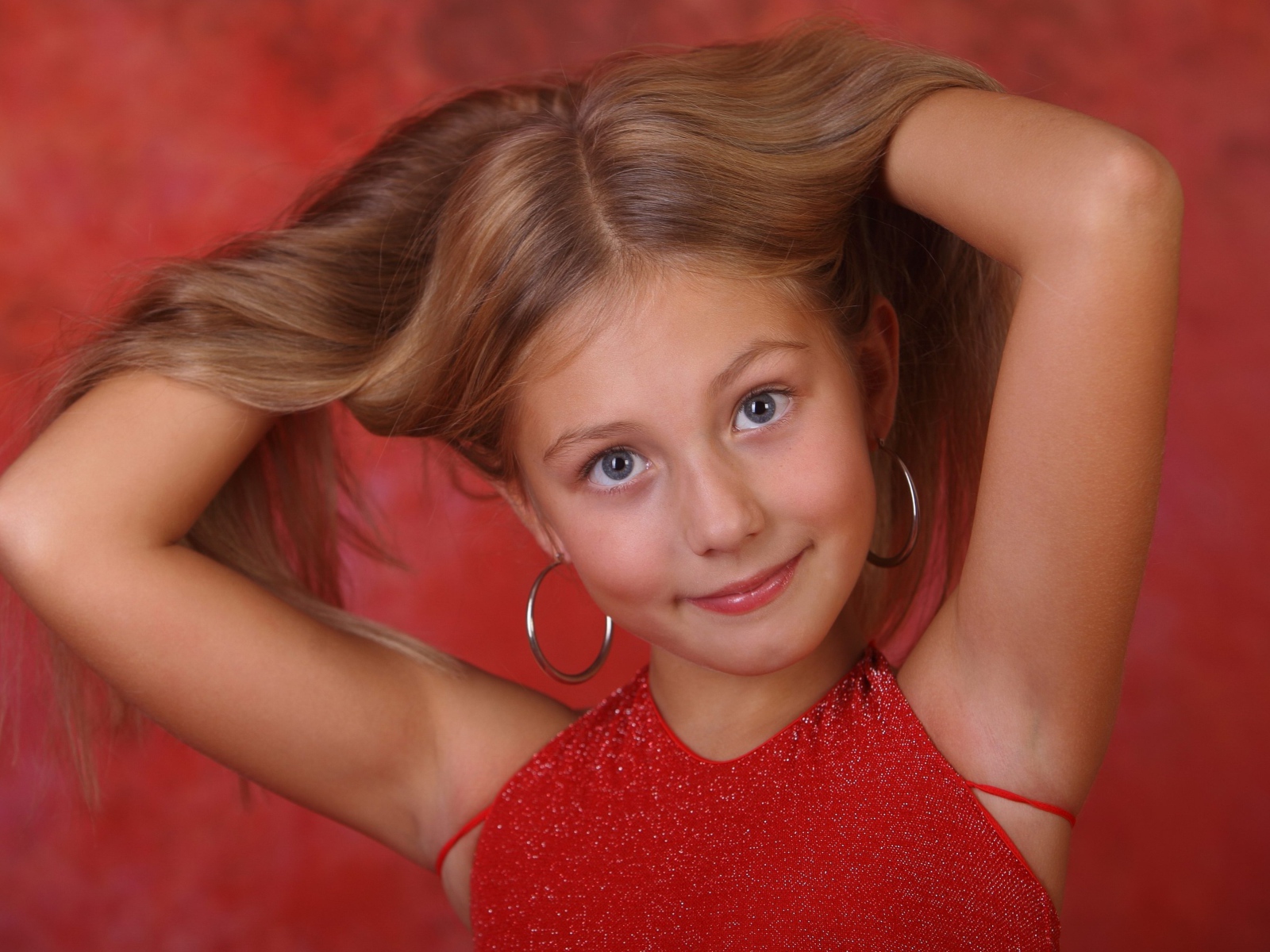 Красивая маленькая девочка с руками в волосах