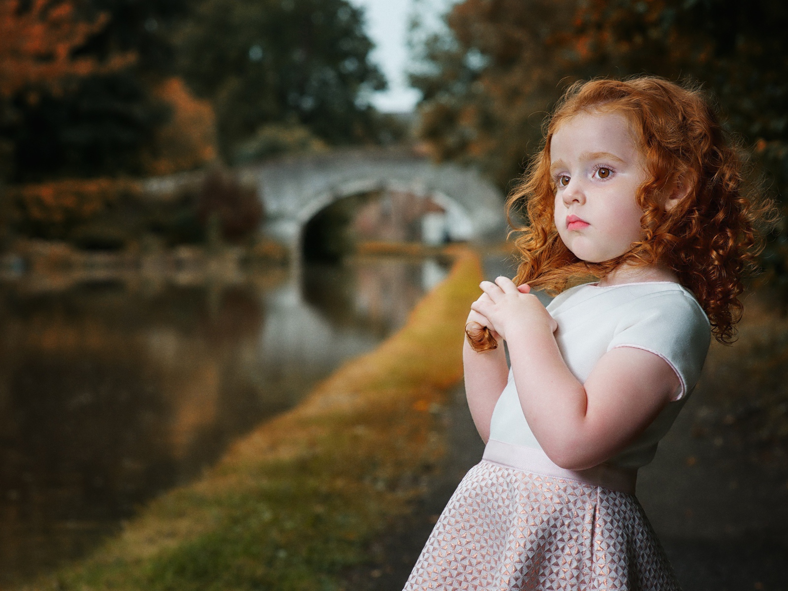 Красивая рыжеволосая девочка у реки в парке 