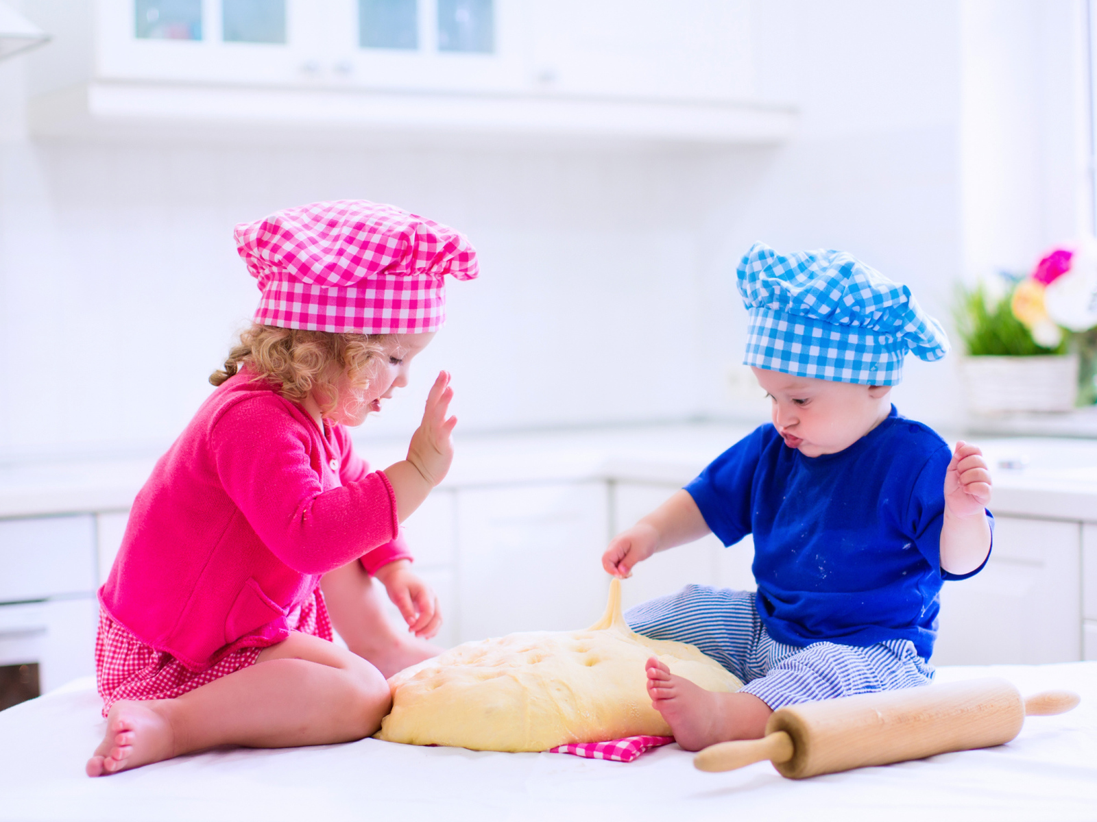 Маленькие мальчик и девочка на кухне с тестом