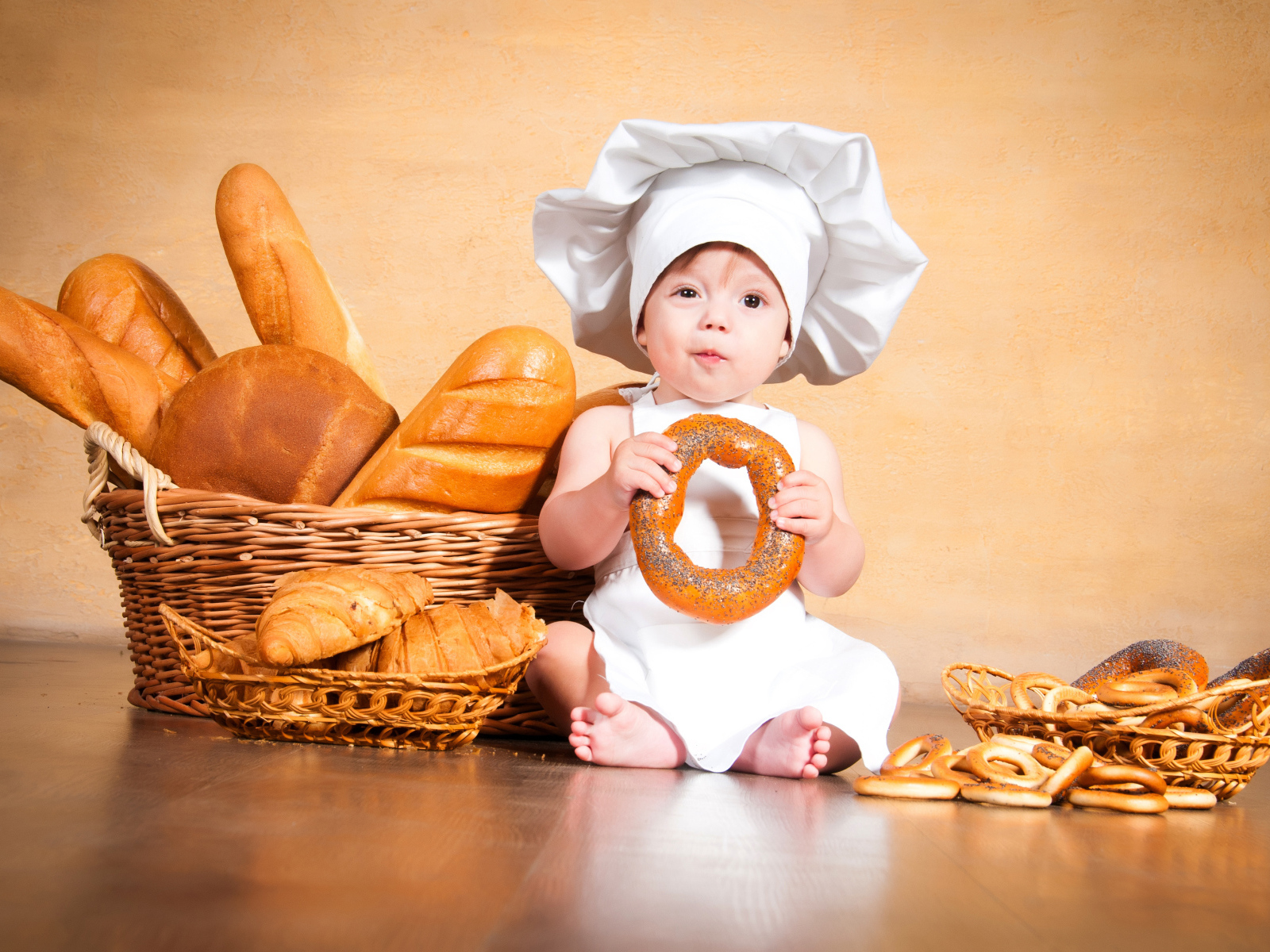 Маленький поваренок на столе со свежей выпечкой