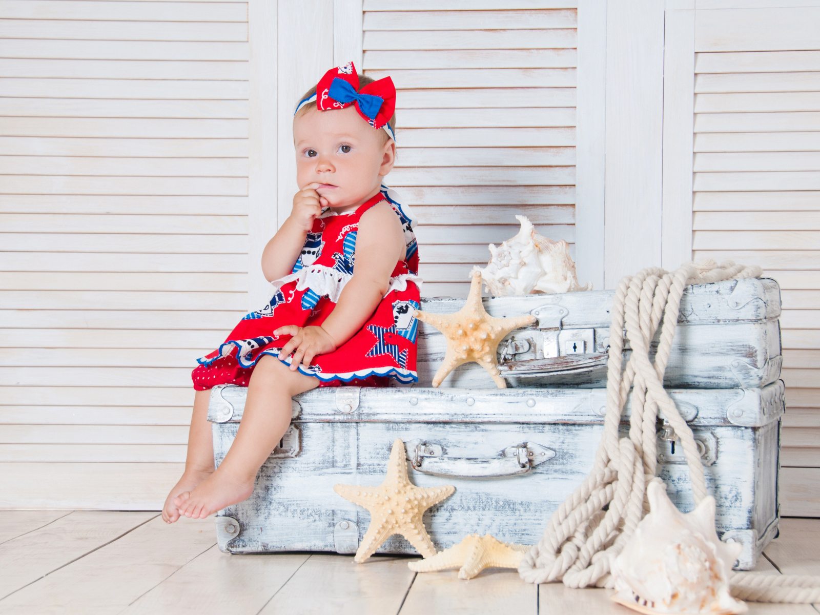 Маленькая девочка сидит на чемодане с морскими звездами