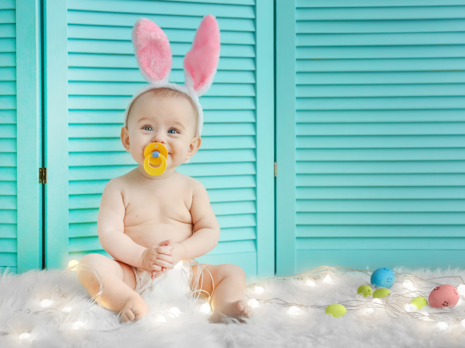 Маленький улыбающийся малыш с ушками зайчика на голове