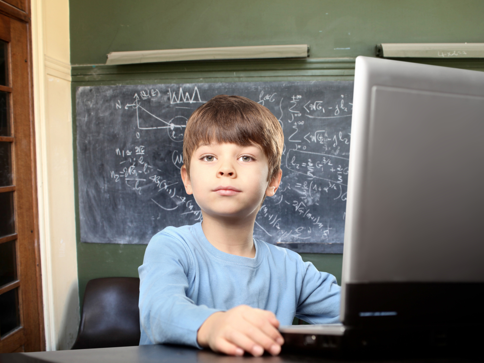 Мальчик школьник делает уроки за ноутбуком