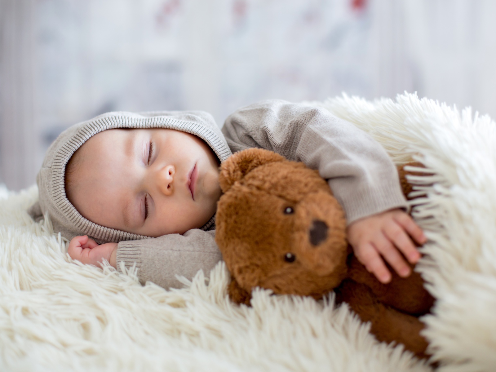 Спящий маленький мальчик обнимает игрушку медвежонка