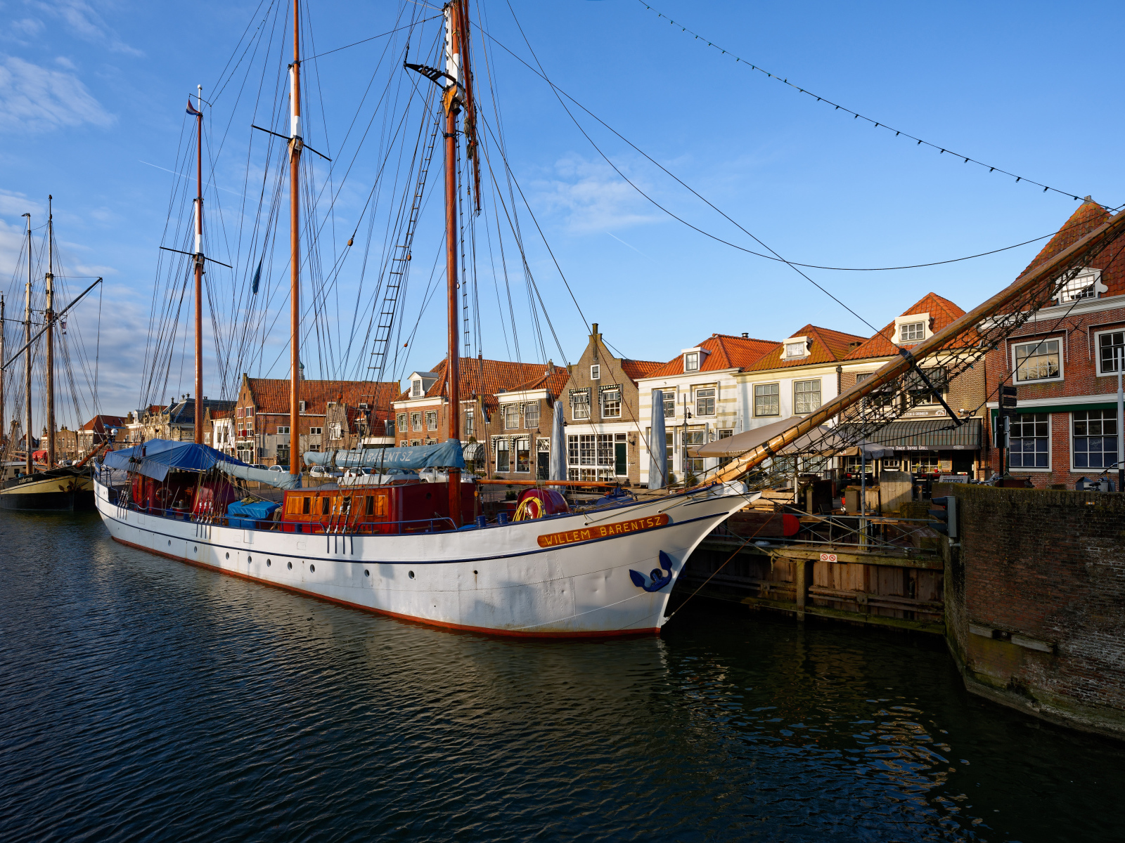 Парусное судно Willem Barentsz с опущенными парусами на причале у домов
