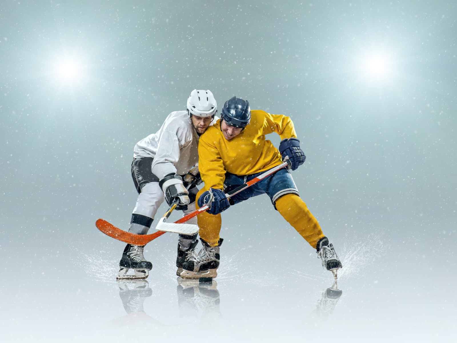 Два спортсмена хоккеиста на льду с клюшками
