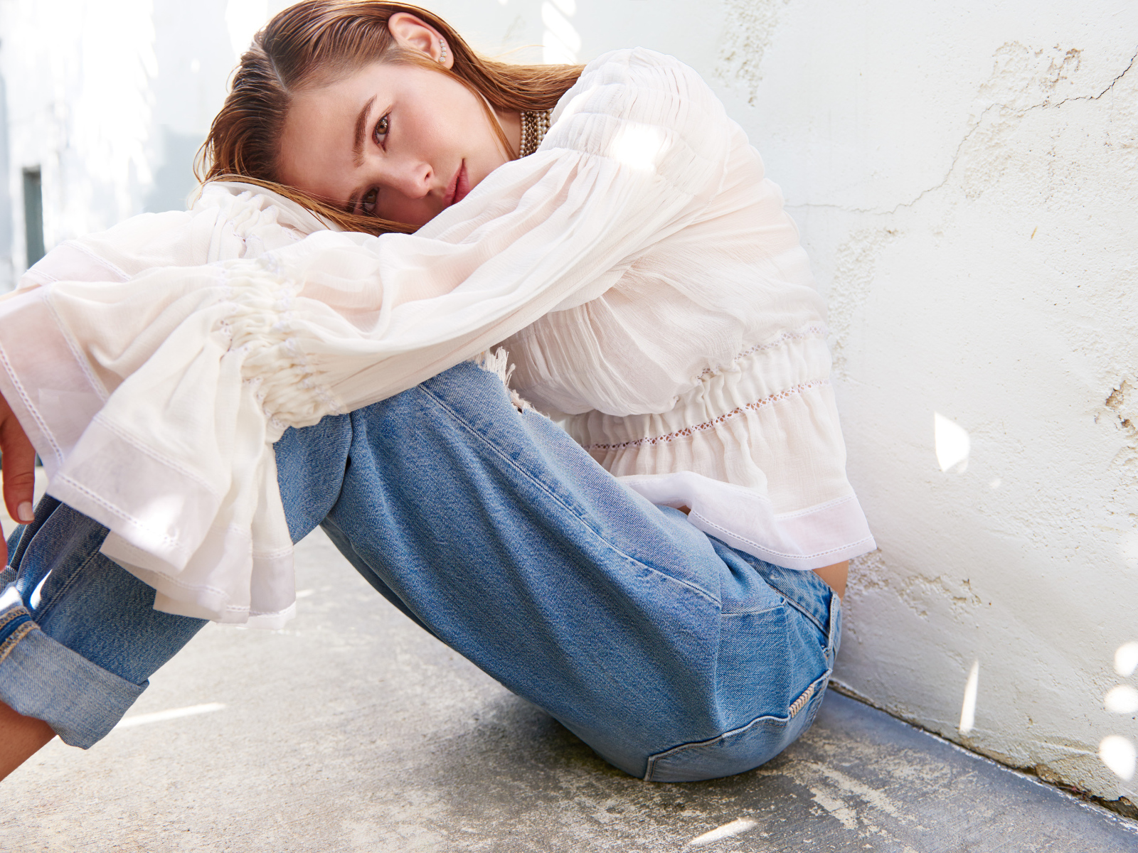 Актриса Зои Дойч сидит у стены