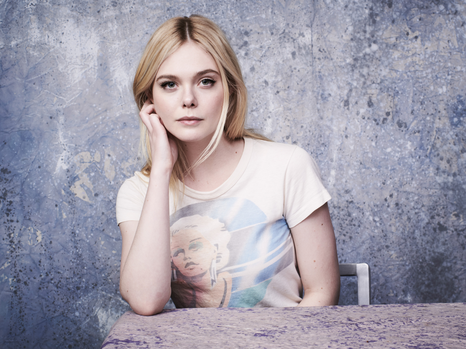 Красивая актриса Эль Фаннинг сидит за столом