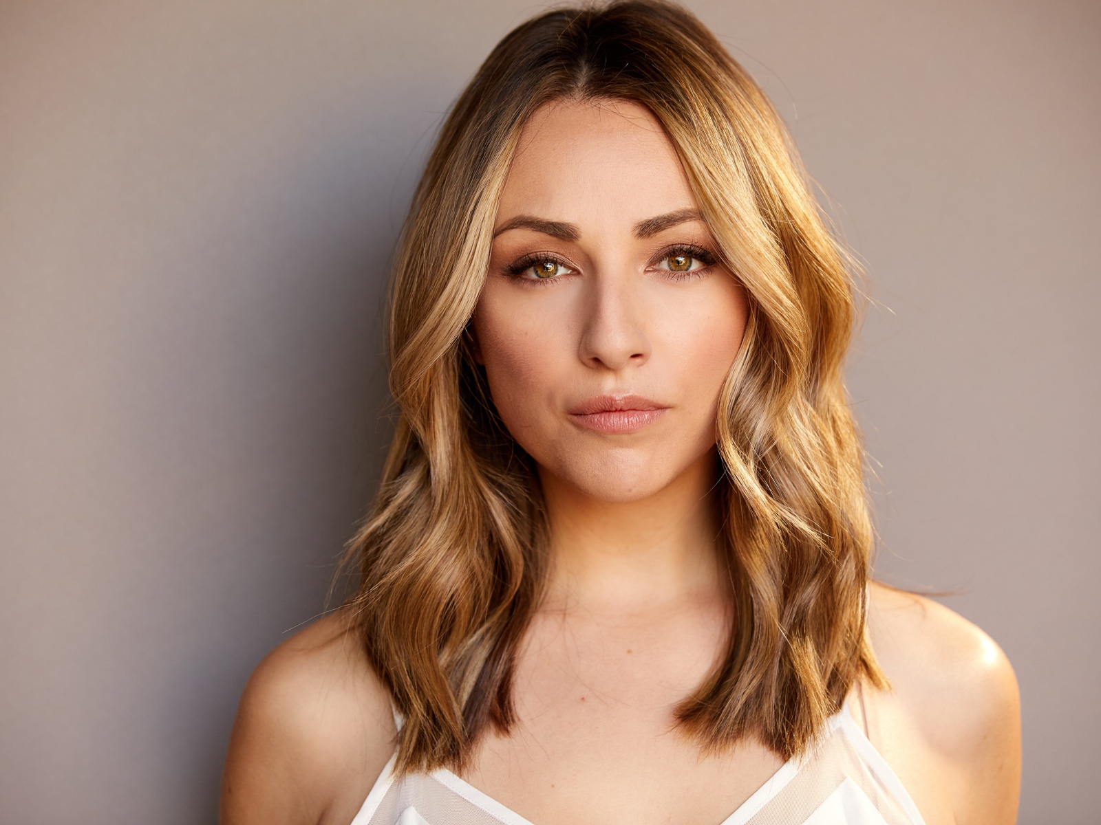 Красивая блондинка Никки Поснер на сером фоне 