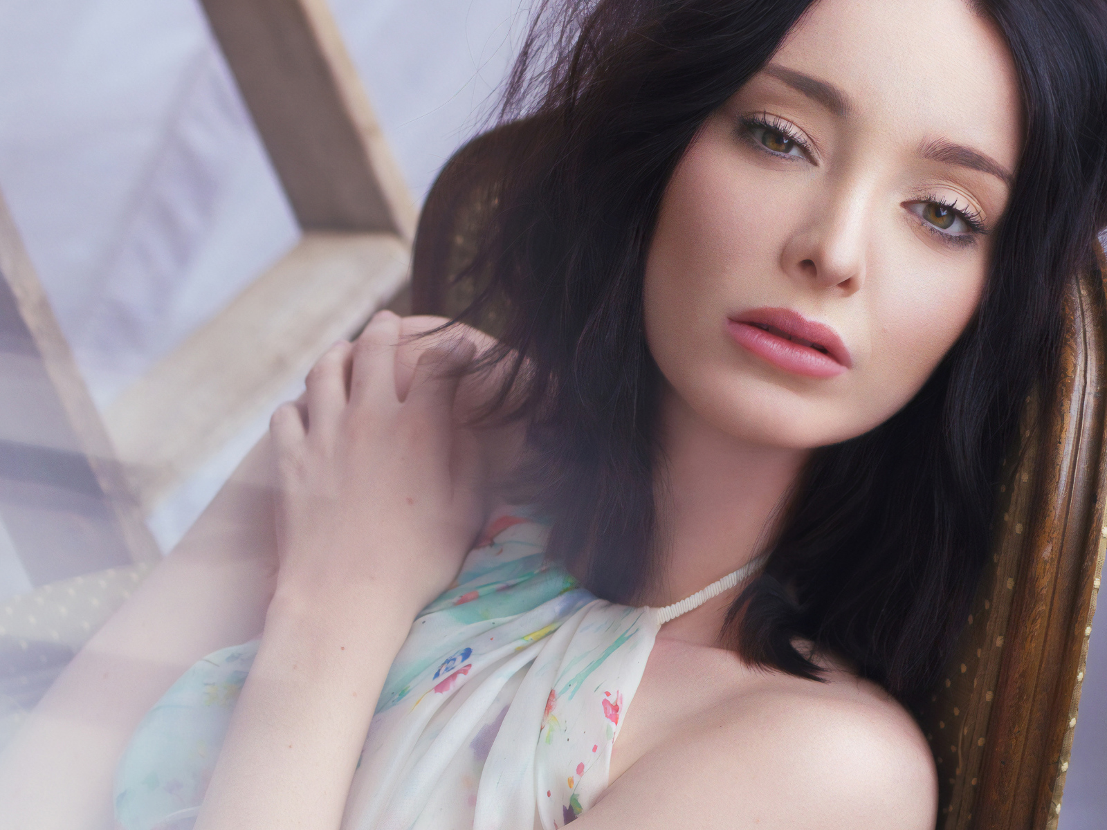 Красивая брюнетка, актриса Эмма Дюмон сидит на стуле 