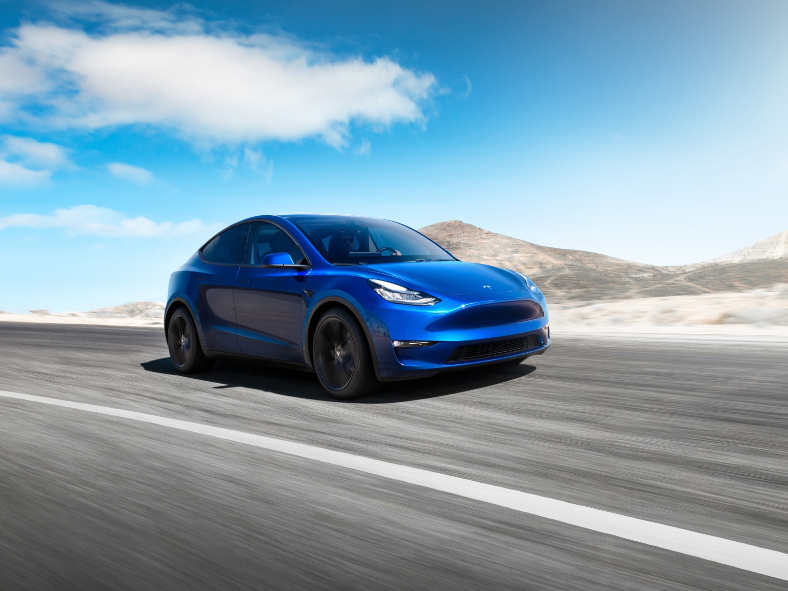 Синий автомобиль Tesla Model Y 2020 года на фоне голубого неба