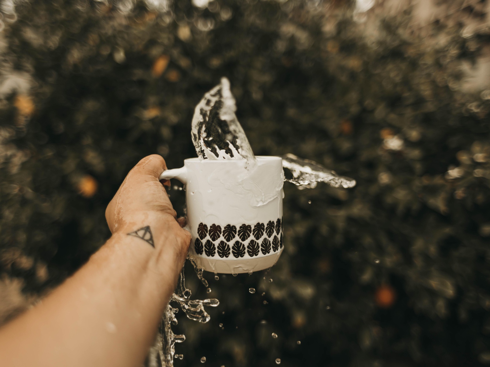 Чашка с водой в руке с татуировкой 
