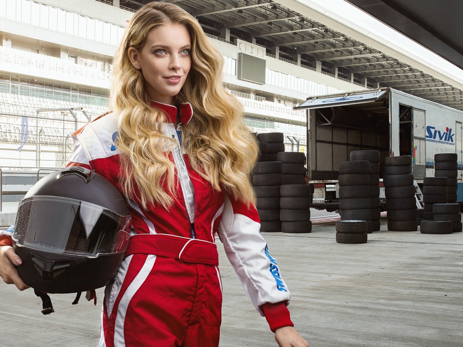 Девушка гонщица с шлемом в руках