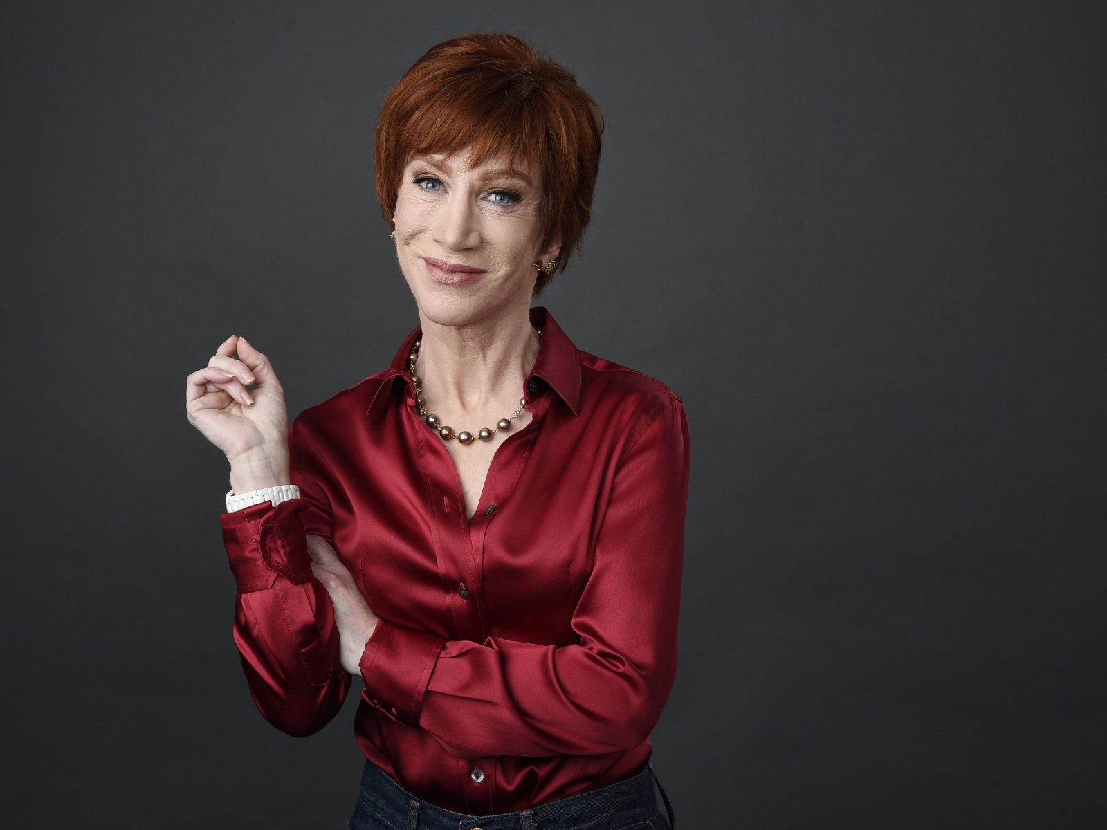 Рыжеволосая актриса Кэти Гриффин в красной рубашке на сером фоне