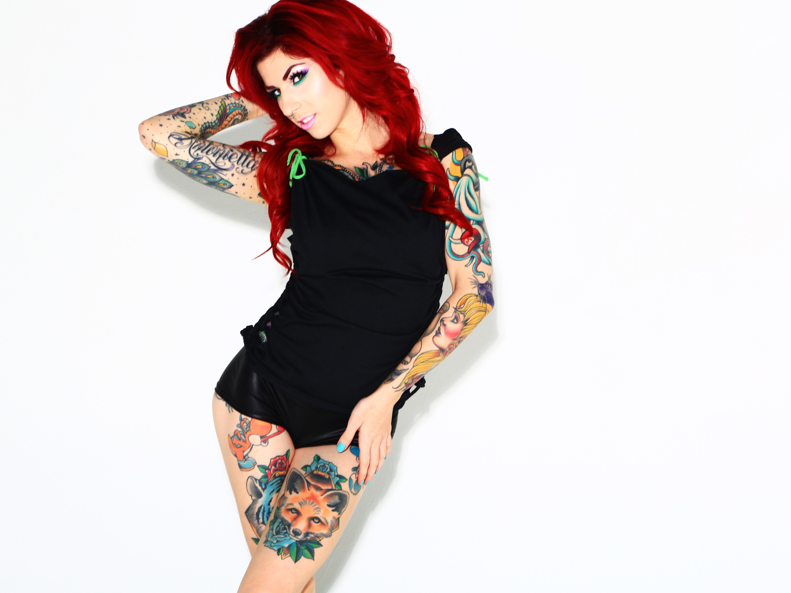 Рыжеволосая девушка с татуировками на теле на белом фоне