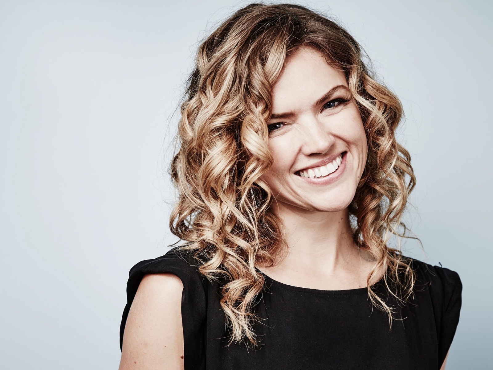 Улыбающаяся блондинка, актриса Эрин Ричардс на сером фоне