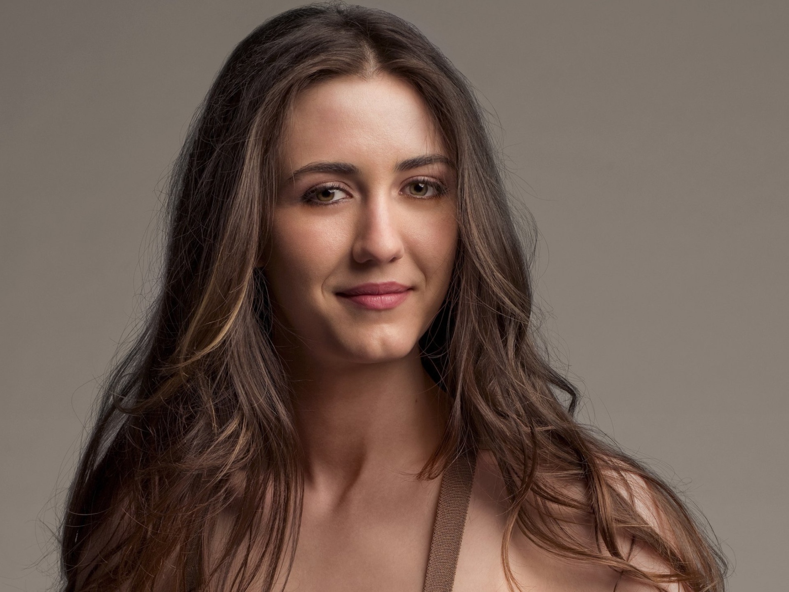 Молодая длинноволосая девушка, актриса Мэйделин Зима на сером фоне