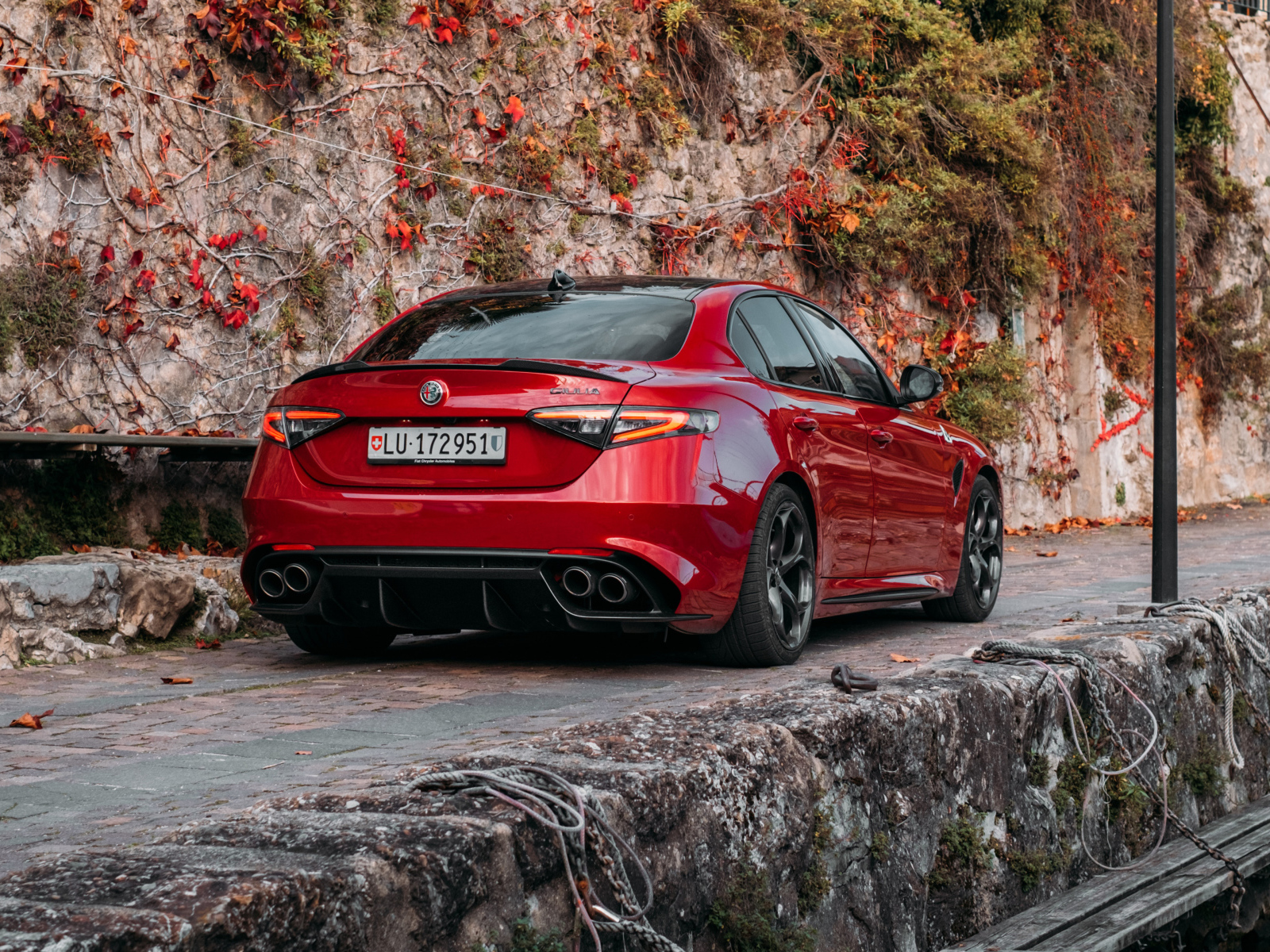 Красный автомобиль Alfa Romeo Giulia Quadrifoglio 2021  года на дороге в горах