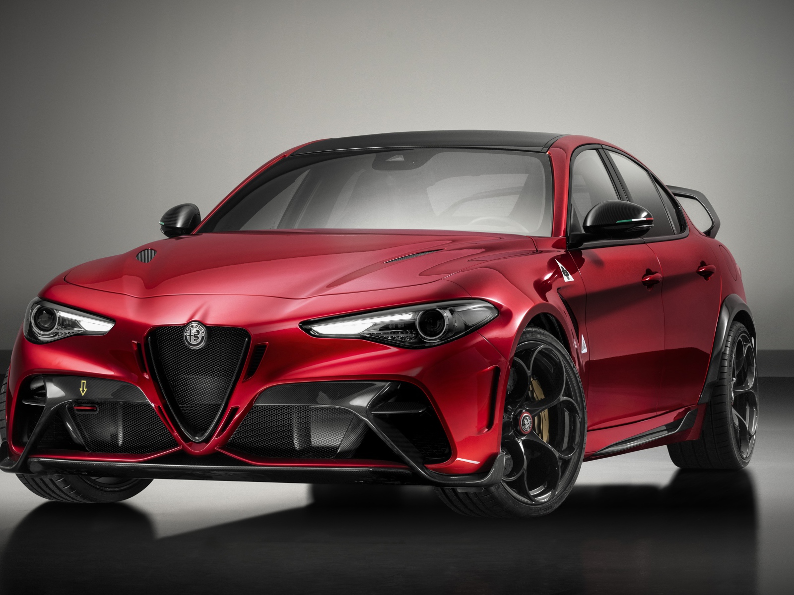 Красный автомобиль Alfa Romeo Giulia GTAm 2020 года на сером фоне