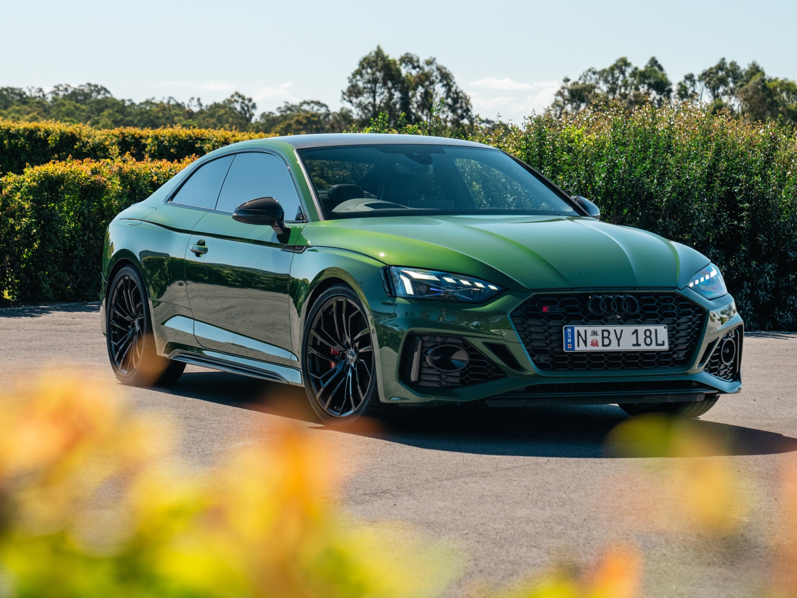 Зеленый автомобиль Audi RS 5 Coupé 2020  года в лучах солнца