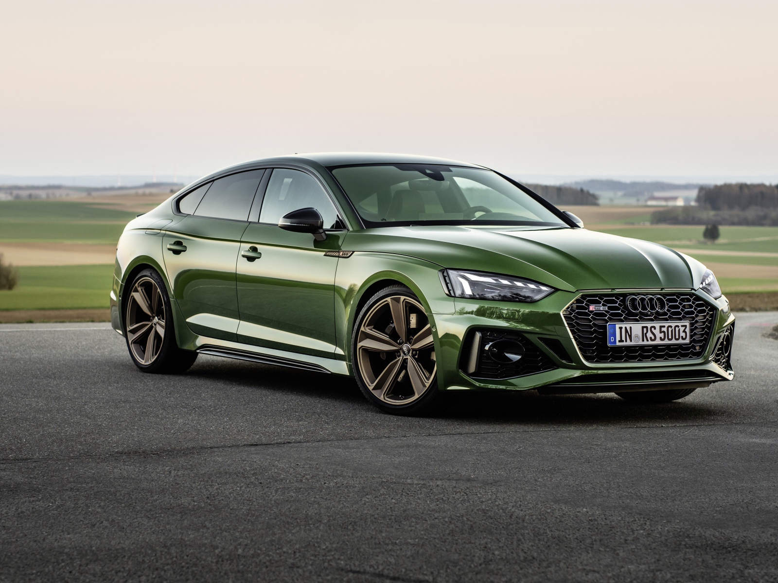 Зеленый автомобиль Audi RS 5 Sportback 2020 года на фоне поля