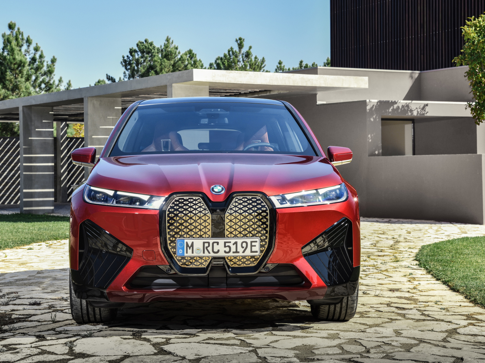 Красный автомобиль BMW IX 2021 года у дома