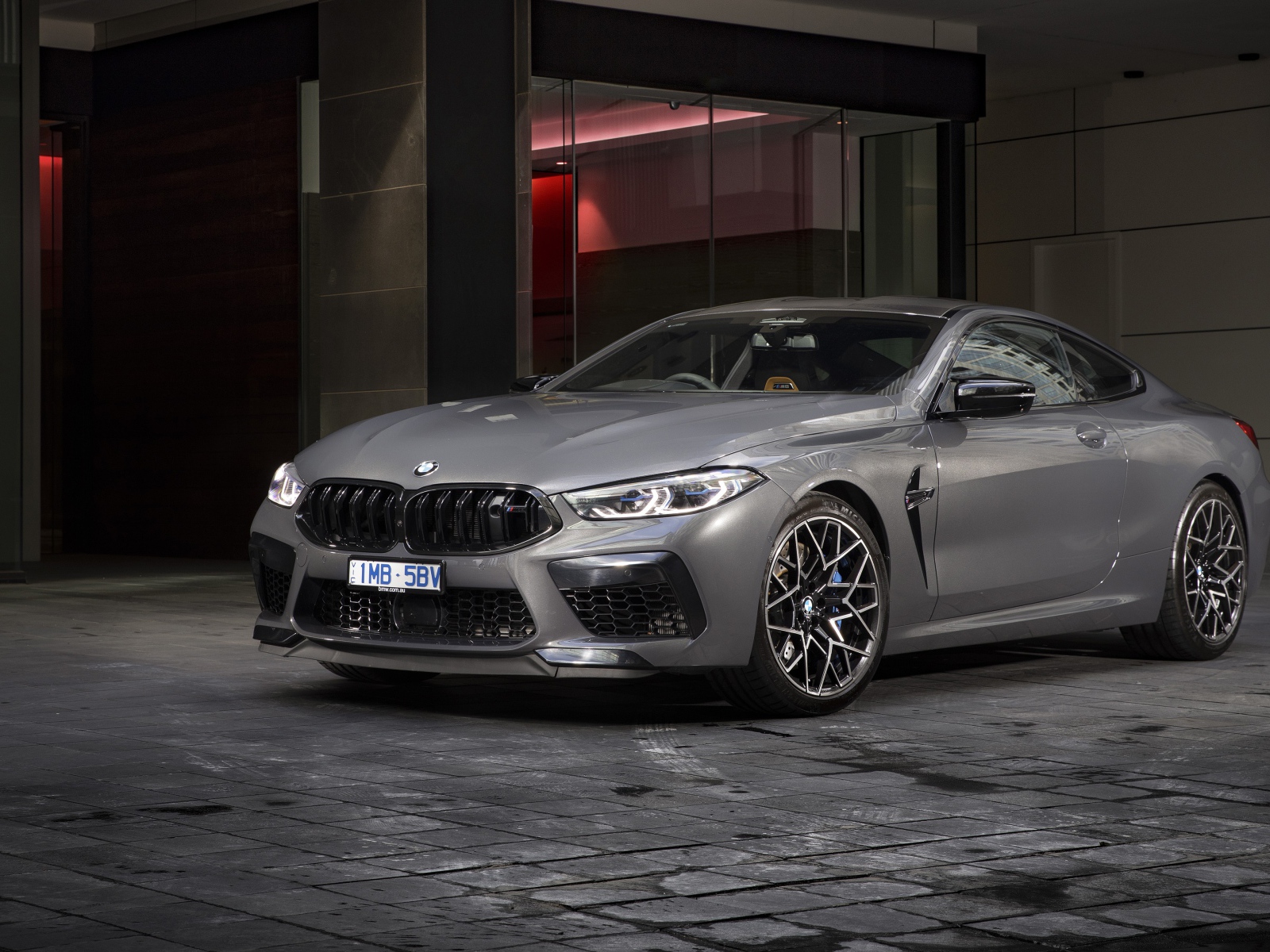 Серебристый автомобиль BMW M8 Competition Coupe 2020 года у здания 