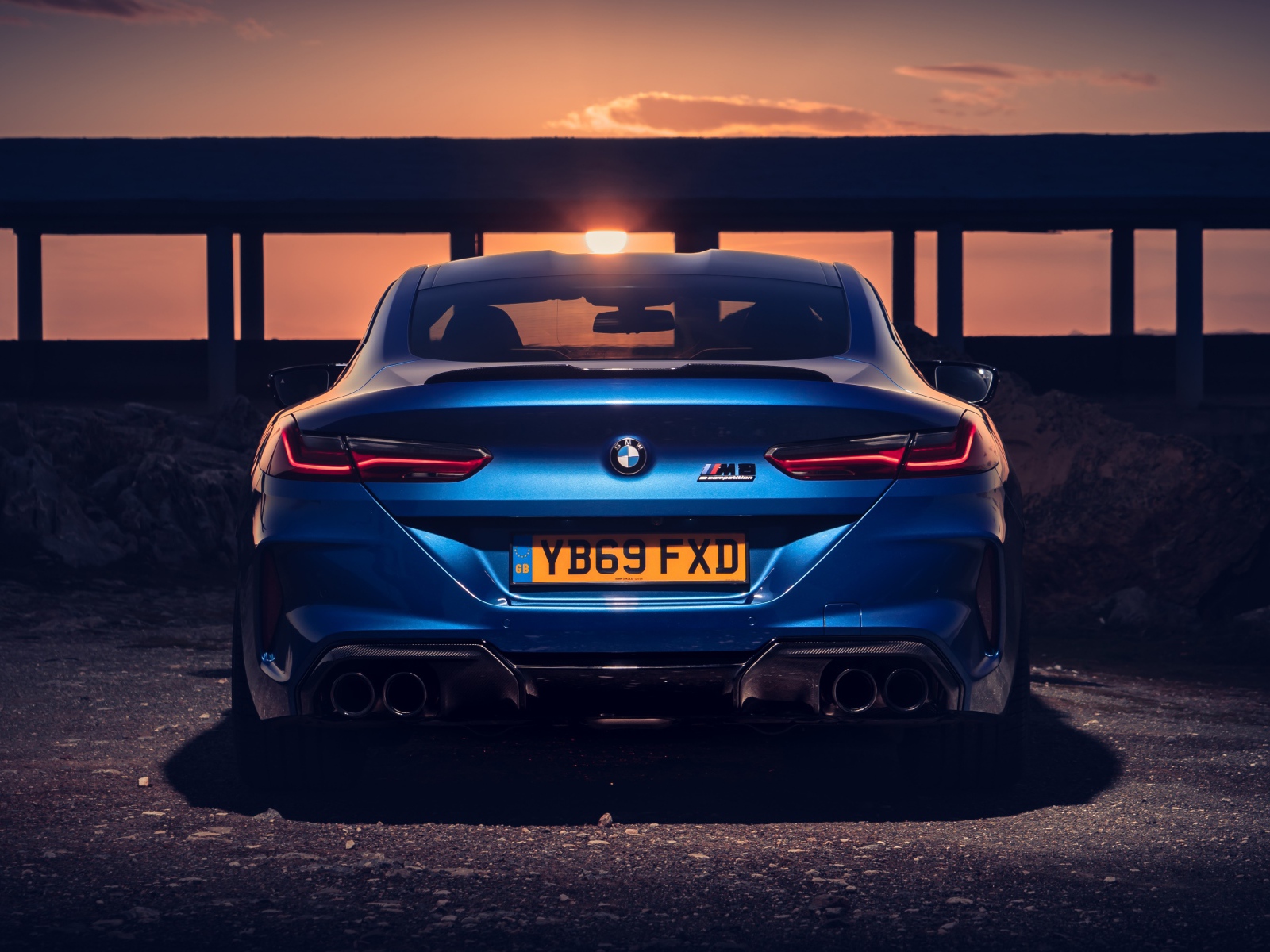 Синий автомобиль BMW M8, 2019 года на фоне заката 