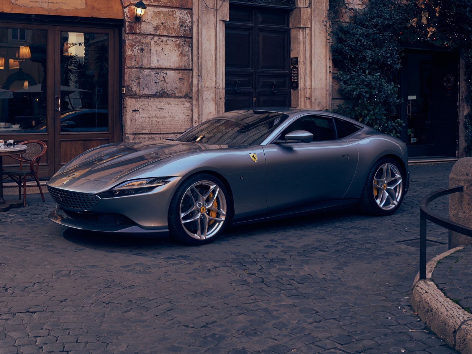 Серебристый автомобиль Ferrari Roma 2020 года у кафе