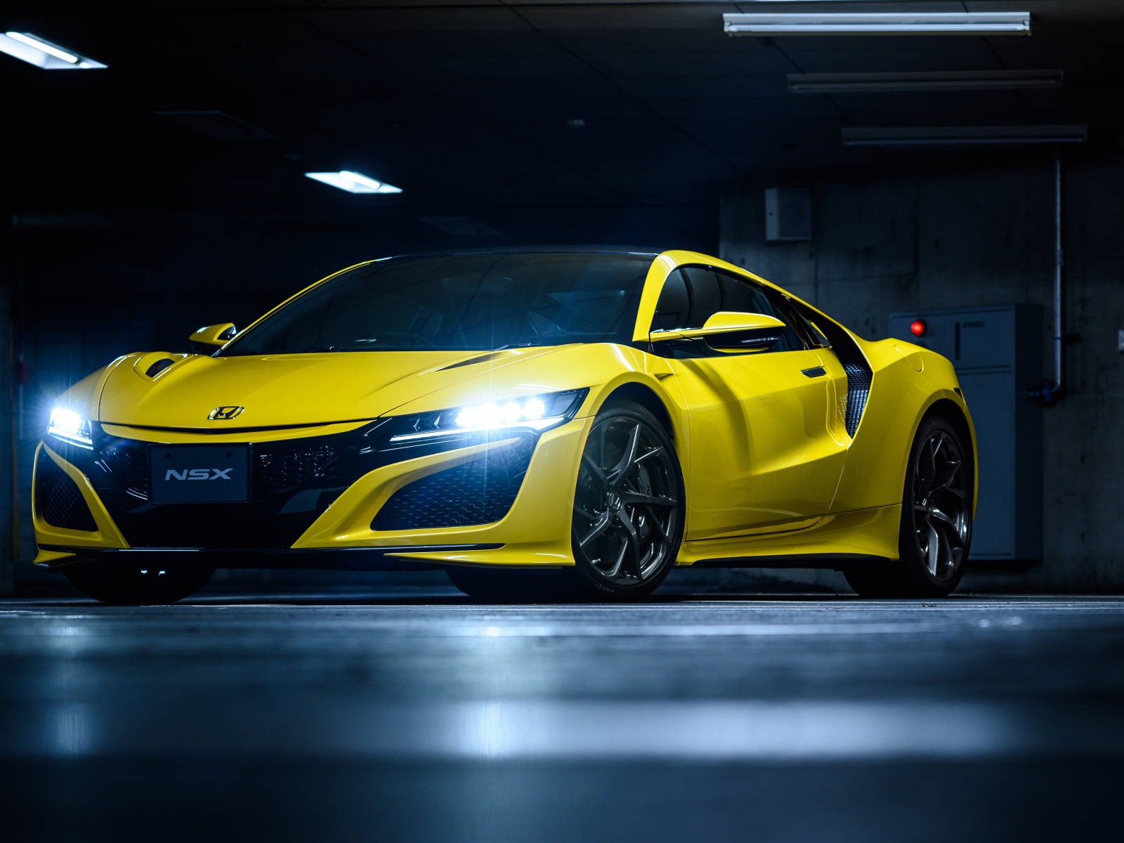 Желтый автомобиль Honda NSX с включенными фарами 