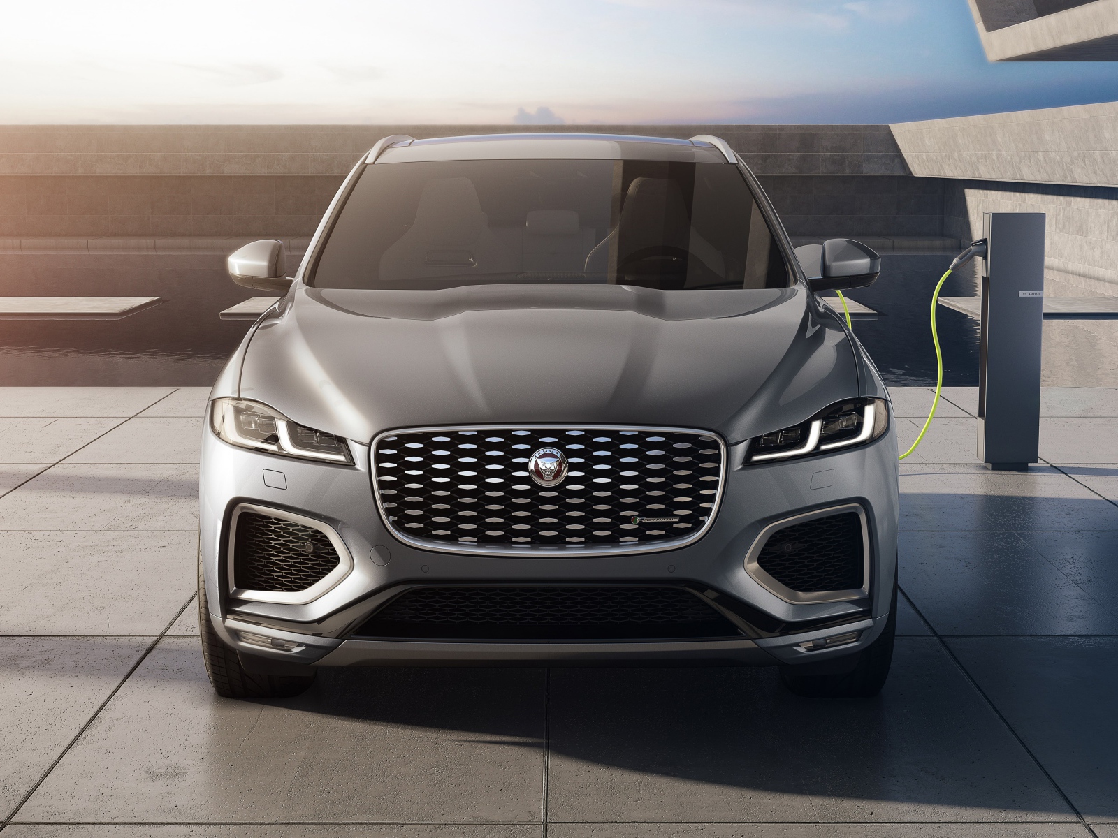 Серый автомобиль Jaguar F-Pace P400e AWD 2020 года на заправке