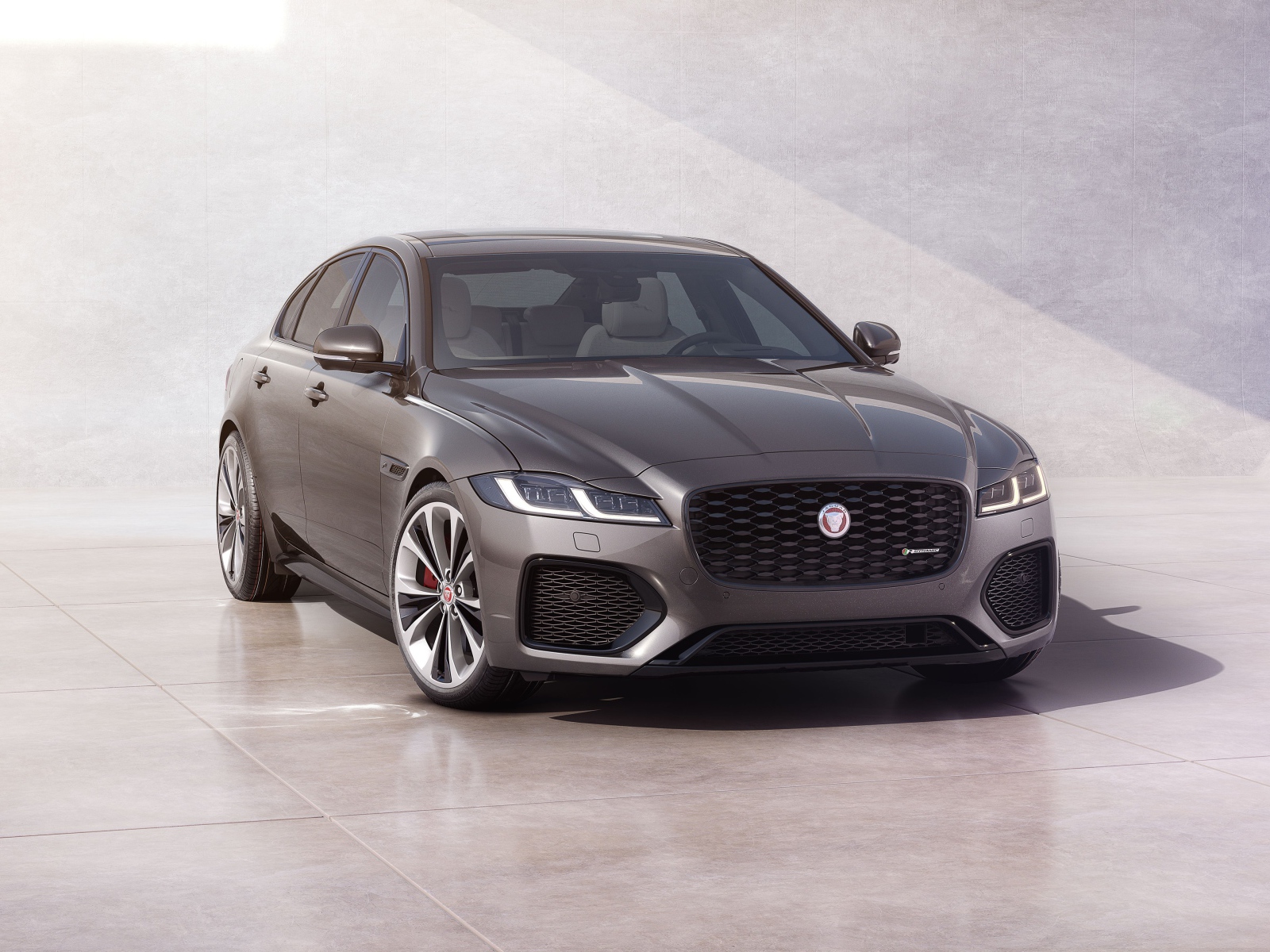 Автомобиль Jaguar XF P300 AWD R-Dynamic 2020 года у серой стены 