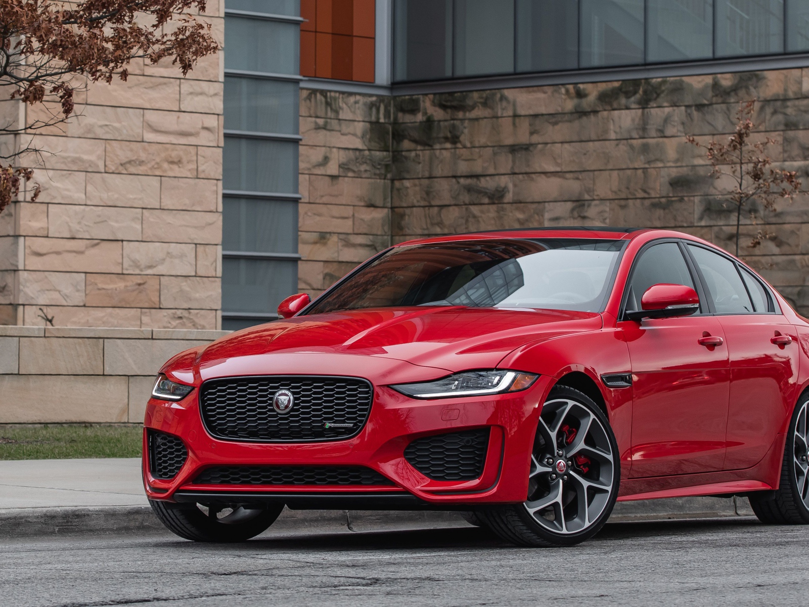 Красный автомобиль Jaguar XE P300 R-Dynamic, 2020 года у здания