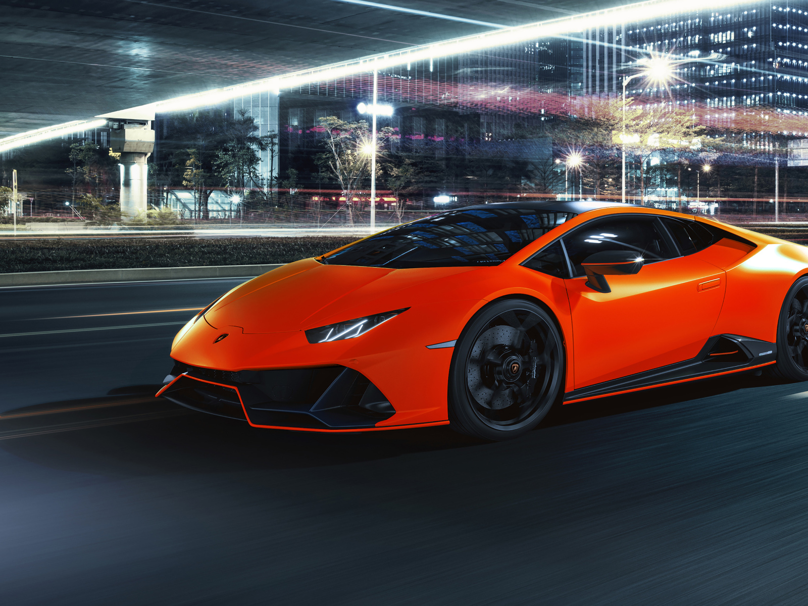 Оранжевый автомобиль Lamborghini Huracán EVO 2021 года на фоне города
