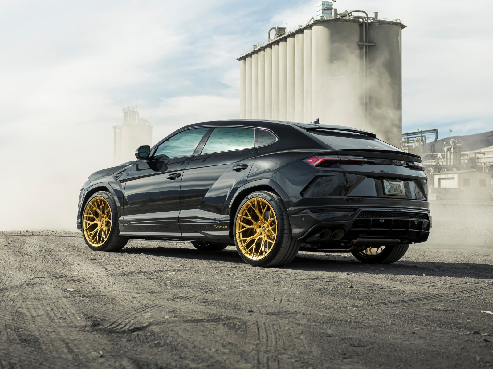 Черный внедорожник  Lamborghini Urus 2020 года на фоне завода вид сзади