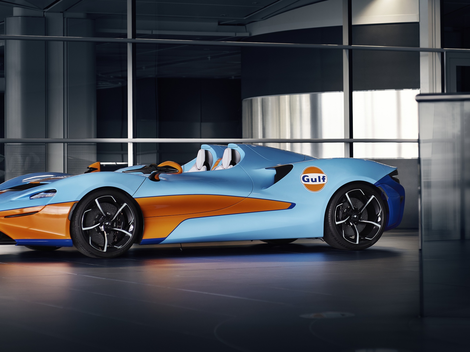 Спортивный автомобиль McLaren Elva Gulf Theme By MSO 2021 года у стеклянной стены 