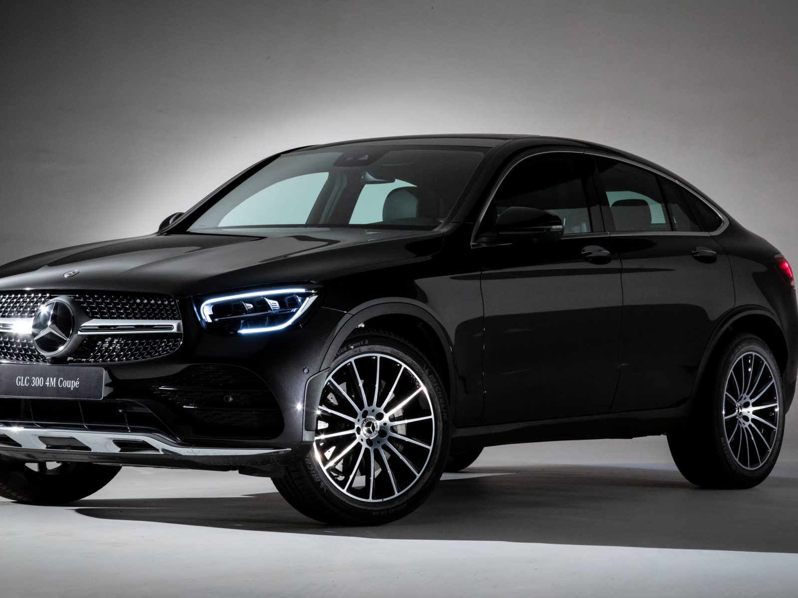 Черный стильный автомобиль Mercedes-Benz GLC 300,  2019 года на сером фоне