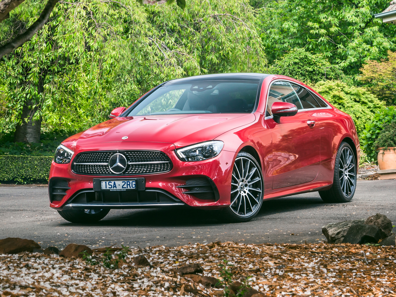 Красный автомобиль Mercedes-Benz E 300 AMG, 2020 года у дома осенью