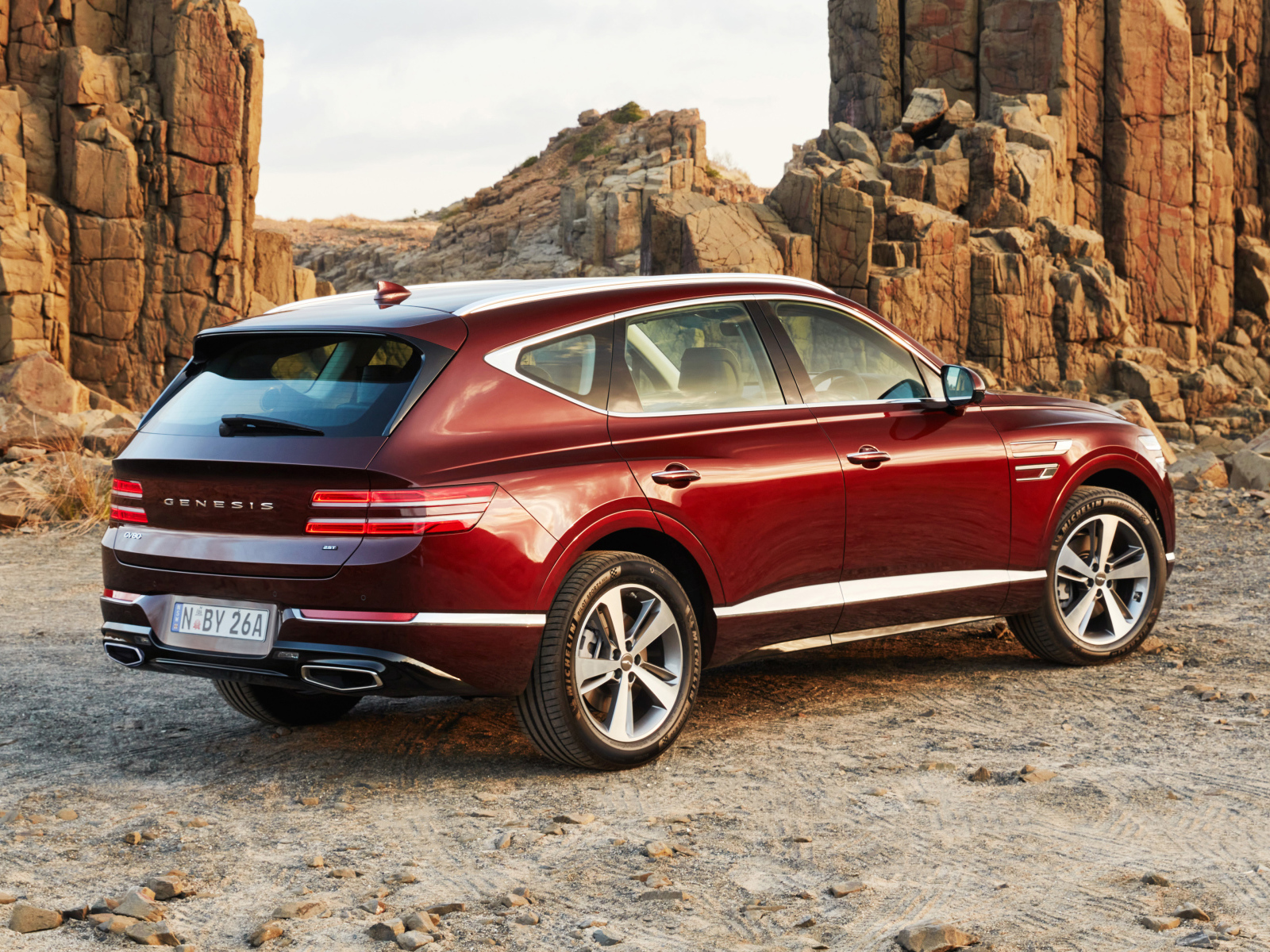 Красный автомобиль Genesis GV80 2.5T 2020 года на фоне гор
